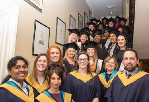 A group of graduates pose for the camera atop a stairs